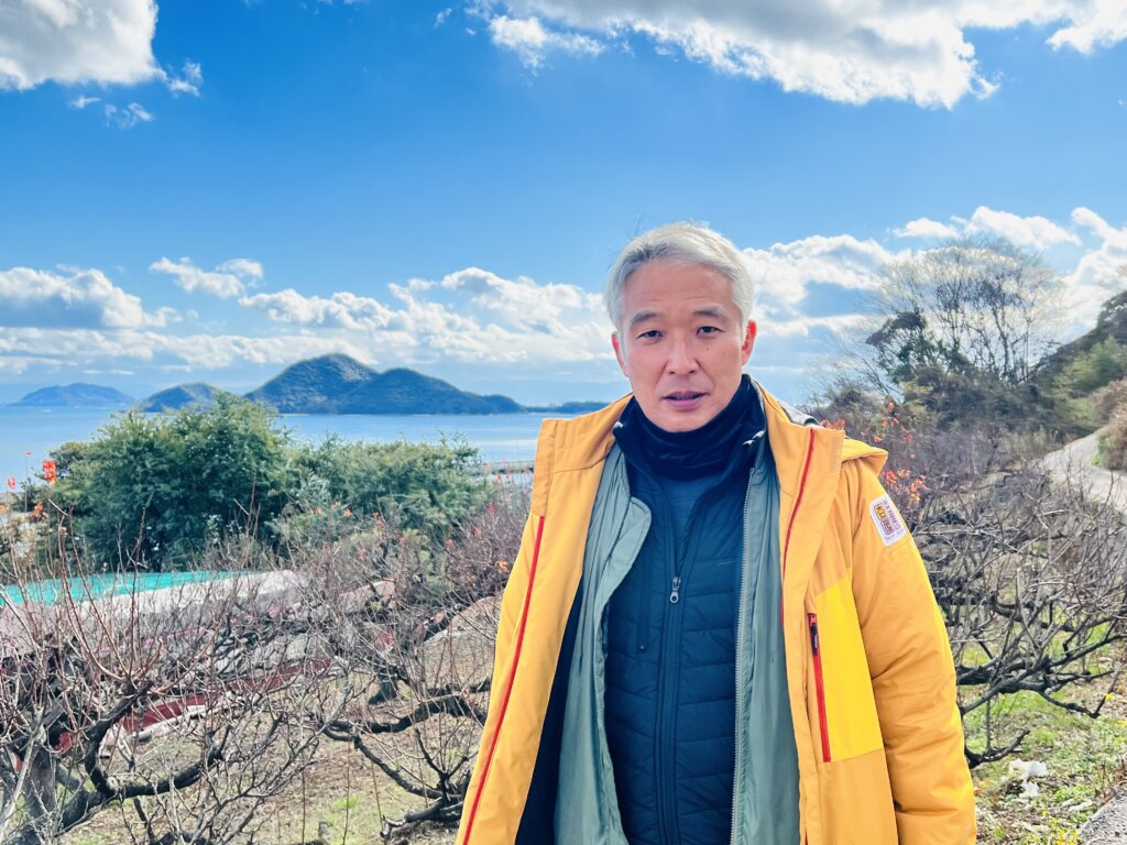 田尻杏屋の男性が杏畑をバックに写っている写真