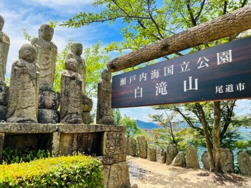 石仏を横に「瀬戸内海国立公園 白滝山」の看板がかかる写真